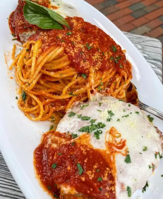 A beautifully plated Italian entrée featuring pasta, seafood, and fresh herbs.