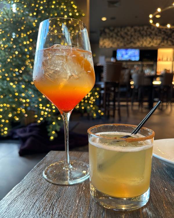 Two colorful cocktails at Galliano Italian Restaurant & Wine Bar with festive background lighting