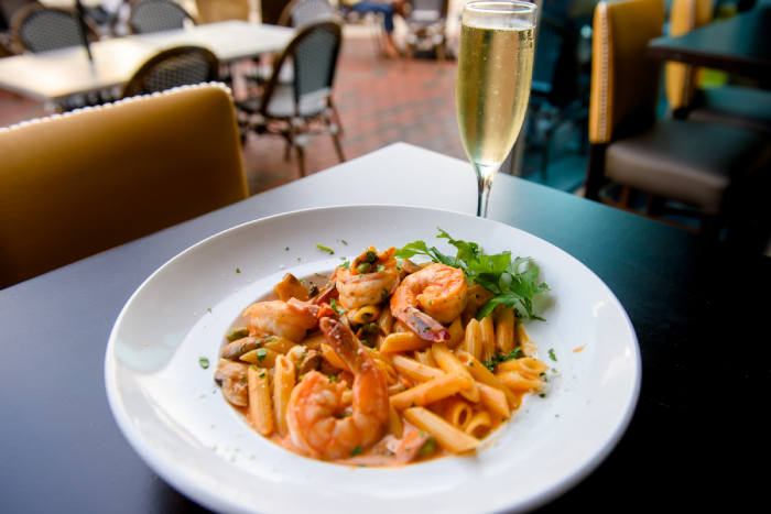 Seafood pasta dish with a cream sauce served with a tall glass of sparkling wine.